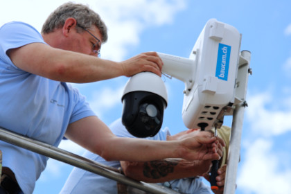 Servicearbeiten an der Baustellenüberwachungskamera welche auf einem Dach an einem Ständer montiert ist.